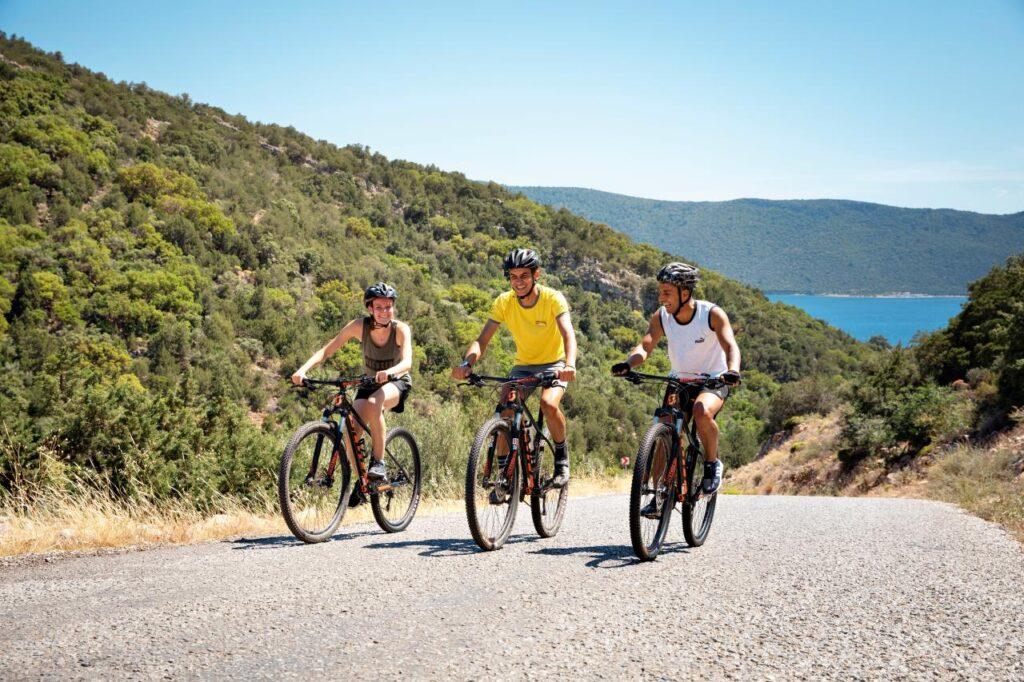 Drei Mountainbiker auf Küstenstraße Türkei mit Meerblick – beste Reisezeit Aktivurlaub TUI MAGIC LIFE Clubs Nebensaison
