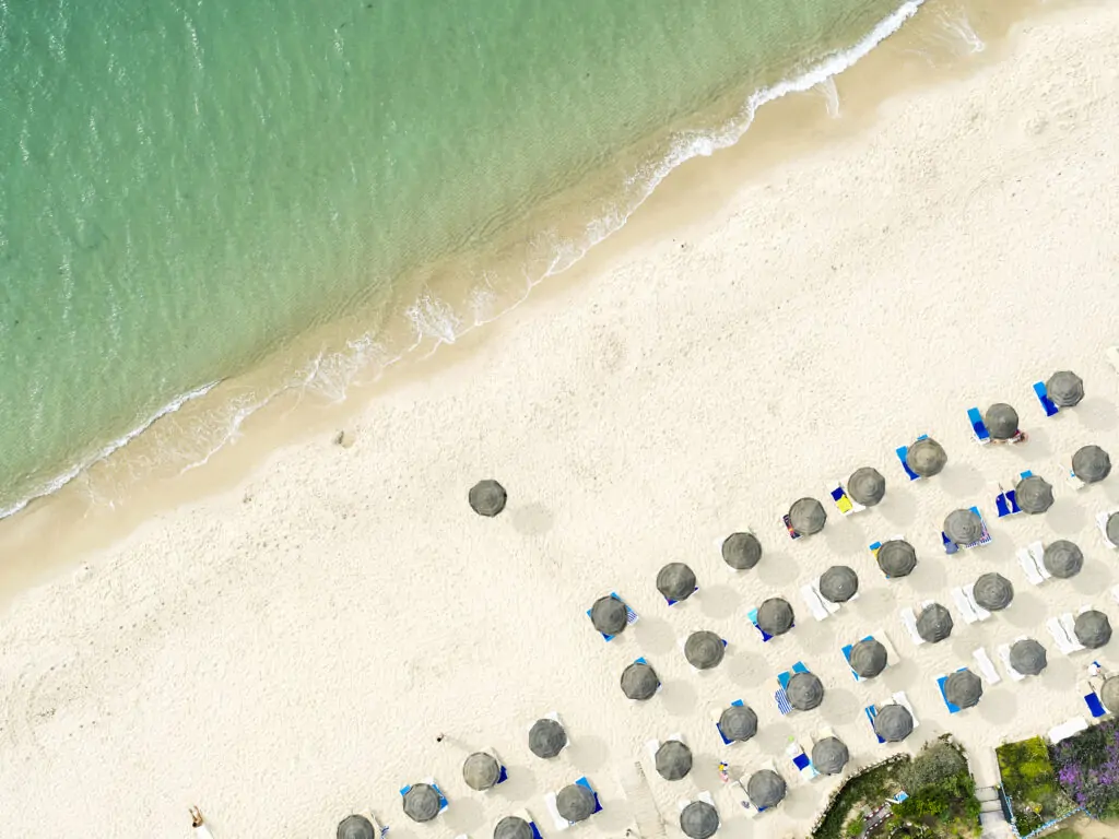 Luftaufnahme des Strands am TUI MAGIC LIFE Africana in Hammamet, Tunesien, mit türkisfarbenem Meer, Sonnenschirmen und Strandliegen.
