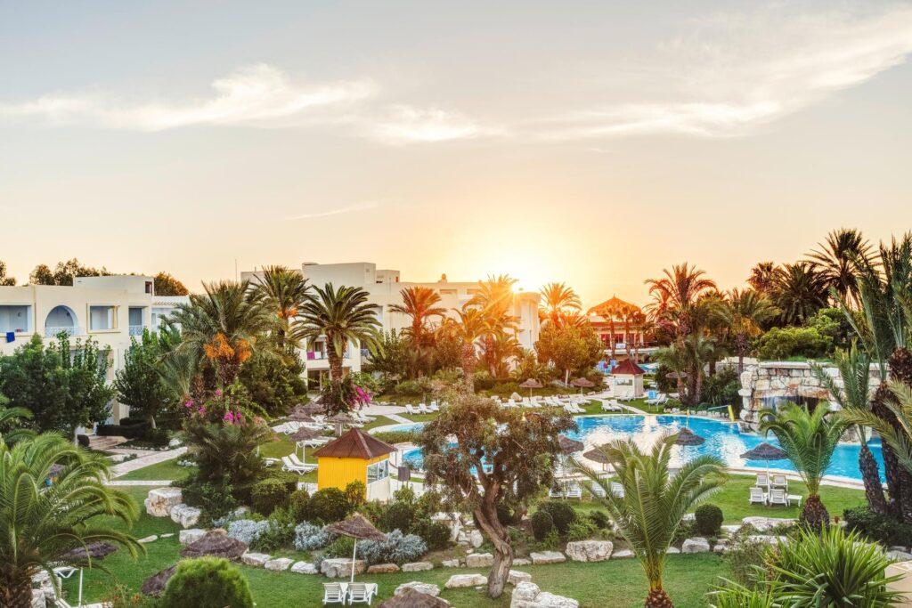 Abenddämmerung im TUI MAGIC LIFE Africana mit beleuchteter Poollandschaft, üppiger Vegetation, Palmen und weißen Hotelgebäuden in Hammamet, Tunesien