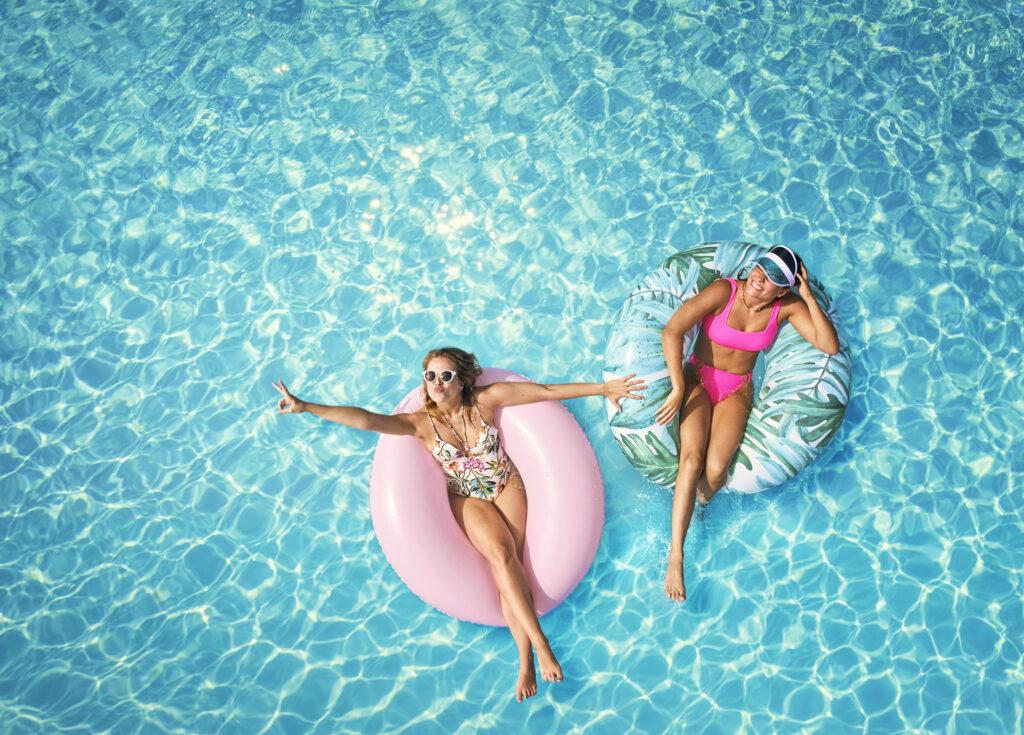 relaxen im Pool auf bunten Schwimmringen – ein sommerliches Szenario, das Lust macht zu überlegen, wann Urlaub machen bei TUI MAGIC LIFE am schönsten ist.