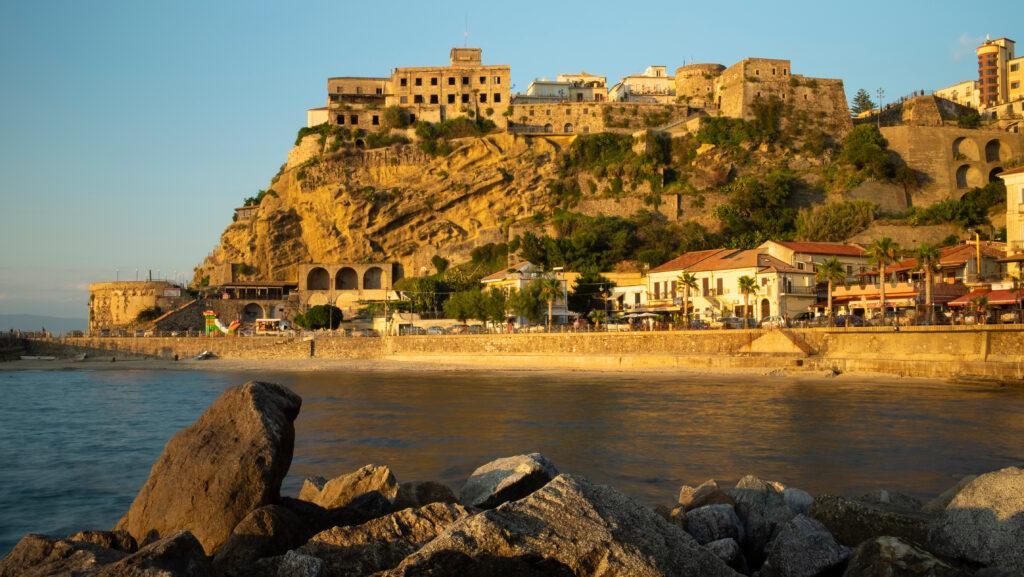 Kalabrien Sonnenuntergang in Pizzo Calabro mit dem historischen Castello Murat aus dem 15. Jahrhundert auf dem Felsen, Strand und Küstenort in warmem Abendlicht, Kalabrien, Italien