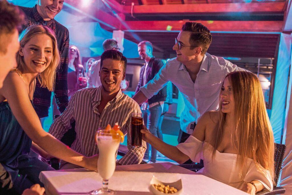 Fröhliche Gruppe Singles bei Party in der TUI MAGIC LIFE Bar ihres Singles Urlaub All Inclusive Resorts