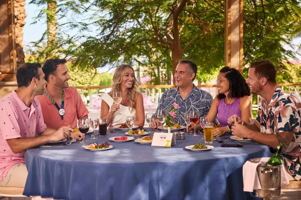 Gruppe von Singles beim gemeinsamen Abendessen im Singles Urlaub All Inclusive Resort unter Palmen