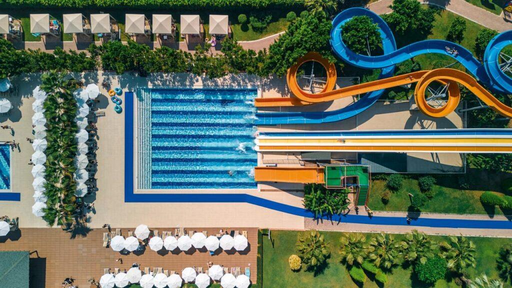 Blick von oben auf den Aquapark im TUI MAGIC LIFE Jacaranda mit farbenfrohen Wasserrutschen, großen Pools und gemütlichen Sonnenliegen.