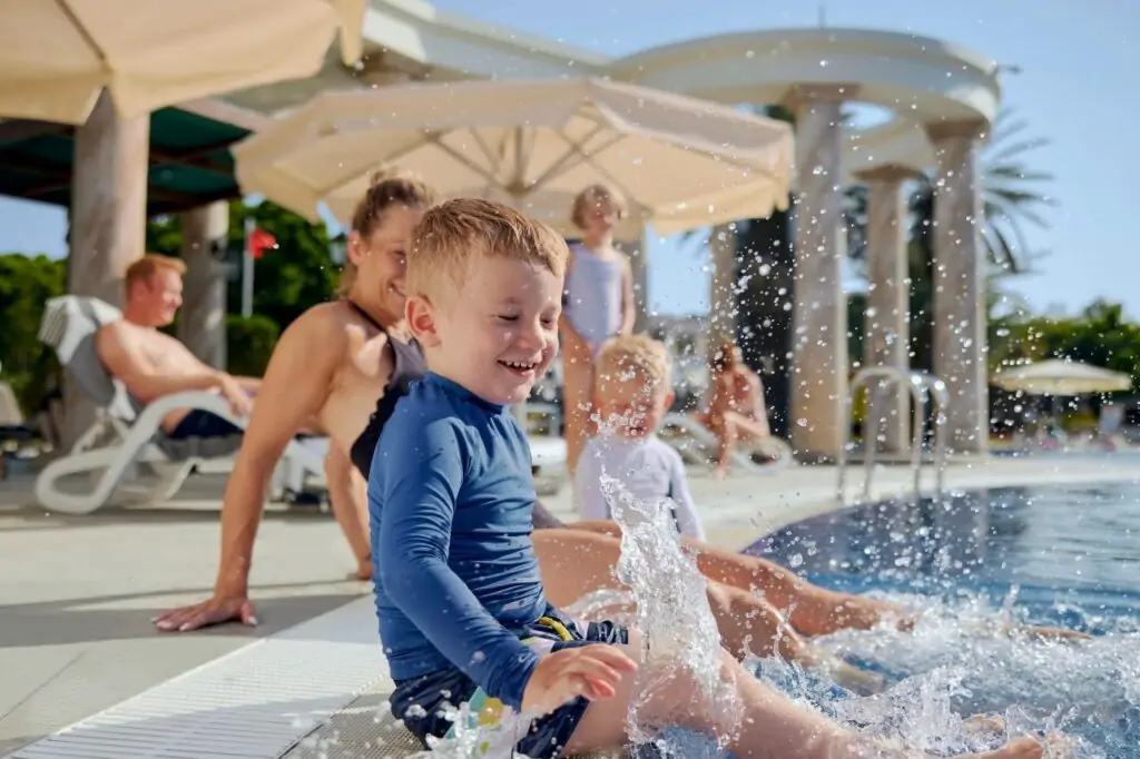 Kinder spielen sicher im flachen Pool bei Swim-up Zimmer Türkei, Familie entspannt im Hintergrund, TUI MAGIC LIFE Familienurlaub