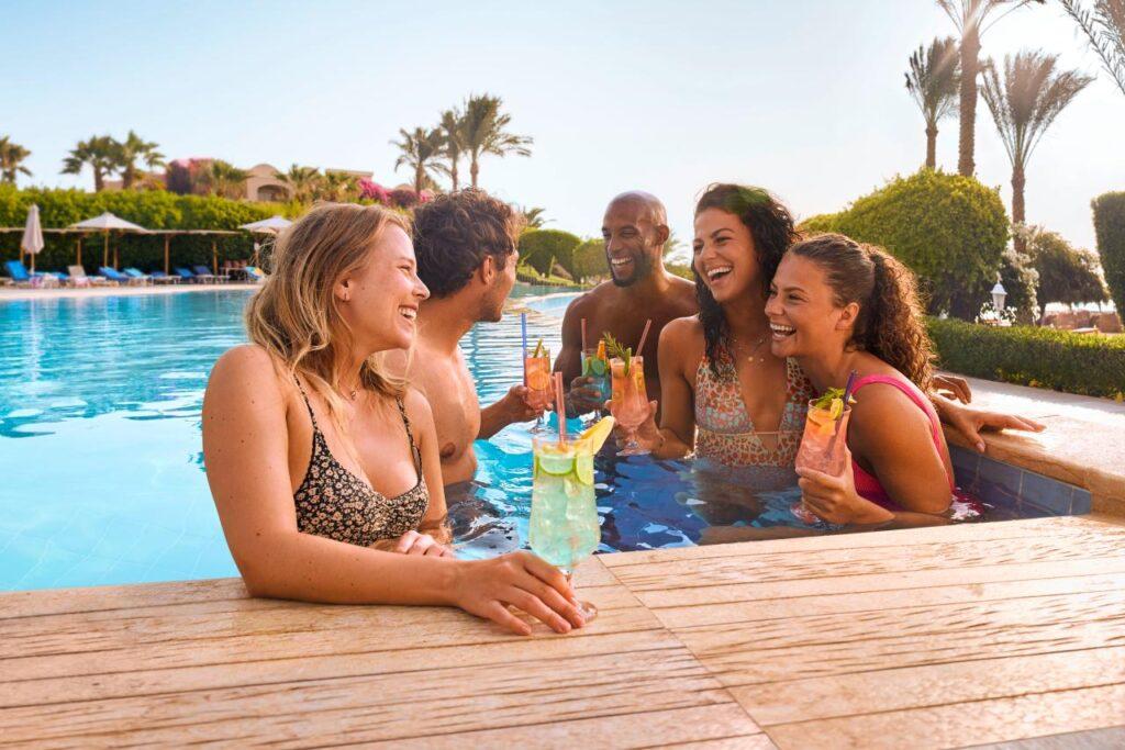 Freundesgruppe mit Cocktails im Pool bei Swim-up Zimmer Türkei, geselliges Beisammensein mit Palmen und Sonnenschein