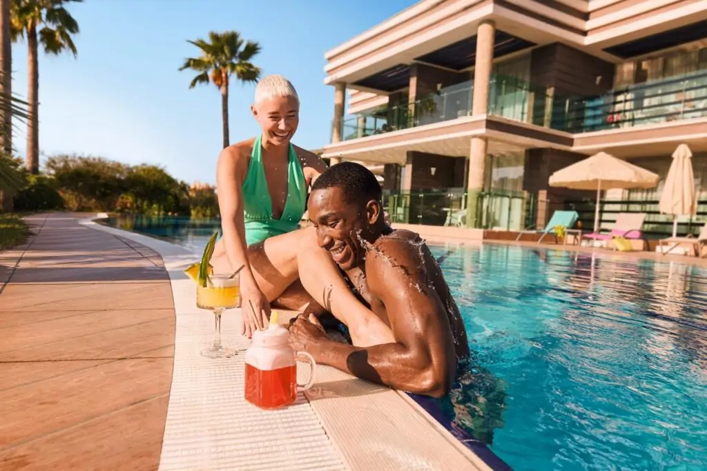 Swim-Up-Zimmer Türkei: Paar mit Cocktails am privaten Pool mit direktem Terrassenzugang, Luxusvilla mit Palmen und Meerblick an der türkischen Riviera, All-Inclusive-Urlaub