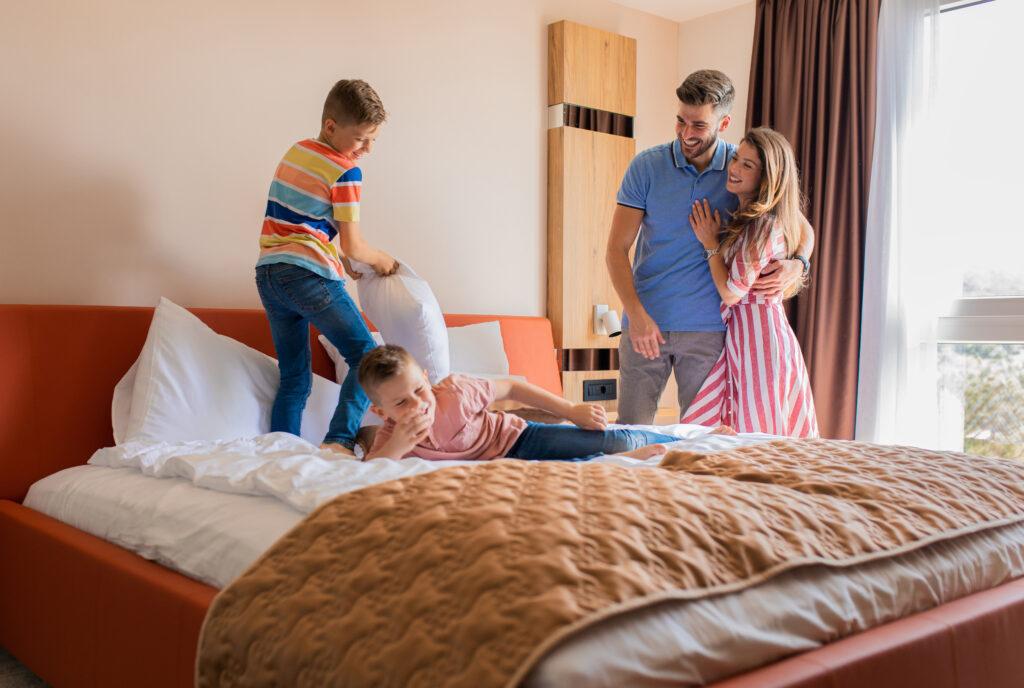 Familie verbringt gemeinsame Zeit im modernen Familienzimmer mit getrennten Schlafzimmern und gemütlicher Einrichtung.