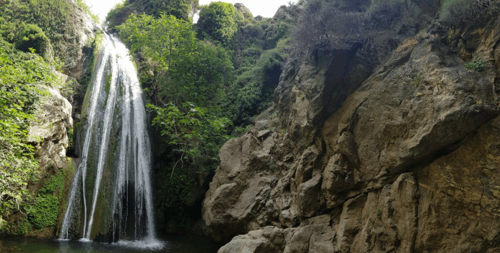 Hoher Wasserfall in der Richtis-Schlucht auf Kreta, umgeben von üppigem Grün und Felsen – ideal für eine erfrischende Wanderung