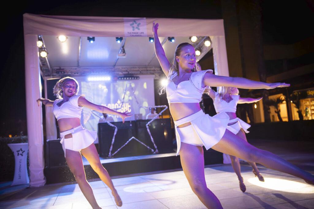 Abendshow im Resort Kalabrien - Performer in weißen Kostümen bei nächtlicher Bühnenshow mit spektakulärer Lichtinszenierung