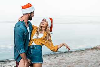 Paar am Strand mit Weihnachtsmannmütze